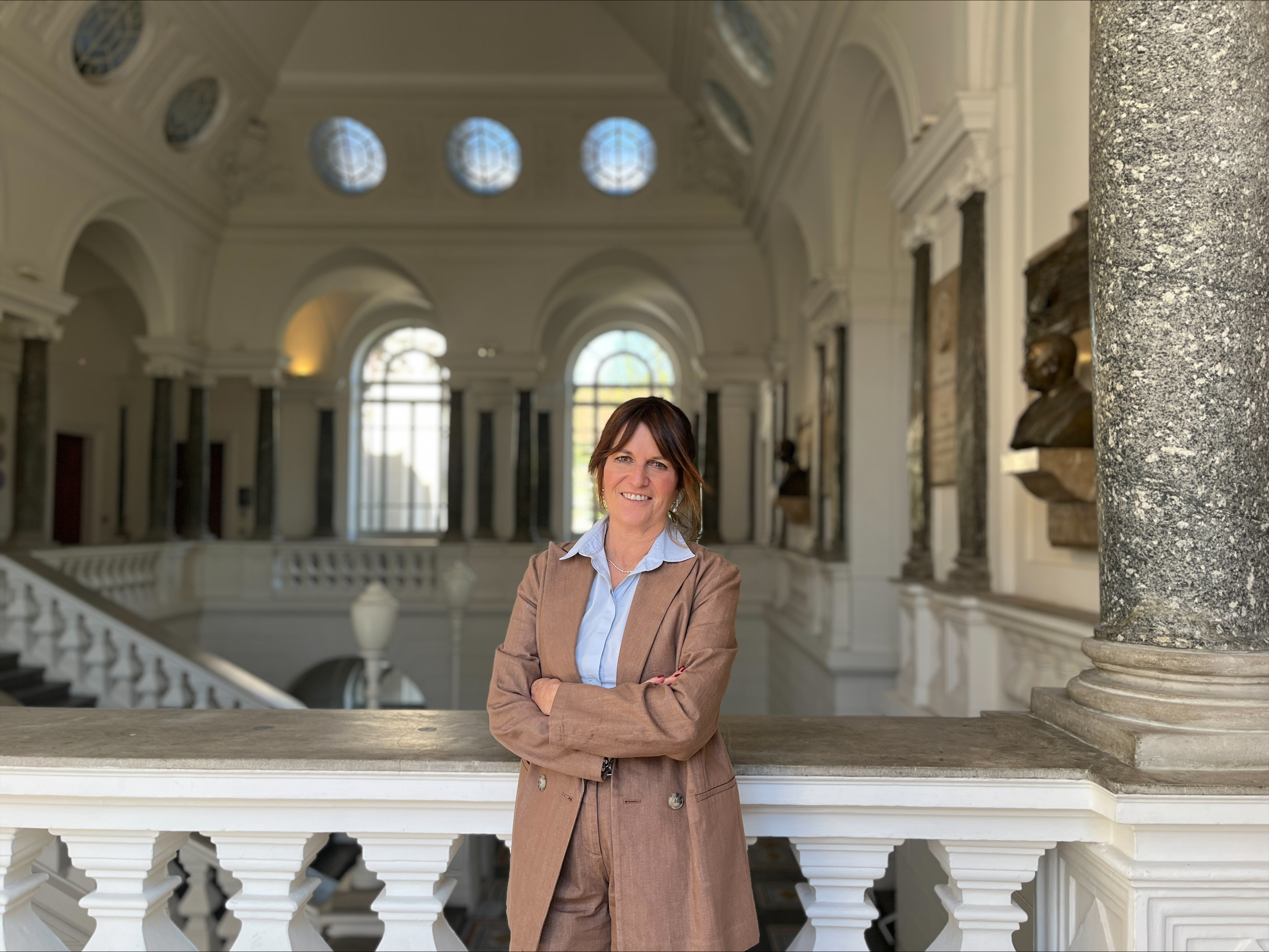 Donna di mezza età con le braccia conserte, sorridente e i capelli legati